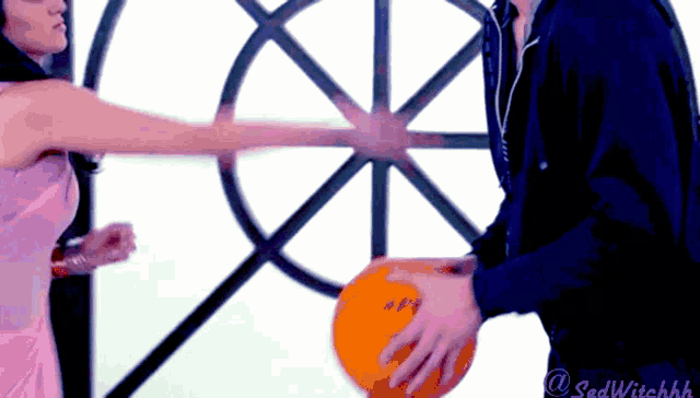 a man and a woman are playing with a basketball with a sad witchhh logo in the corner