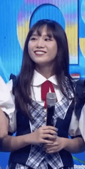 a girl is smiling while holding a microphone in her hand .