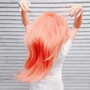 a woman with pink hair is standing in front of a wall