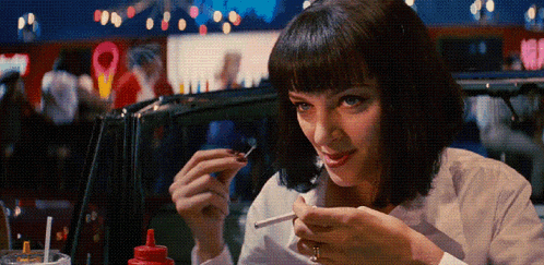 a woman in a white shirt is smoking a cigarette in a diner