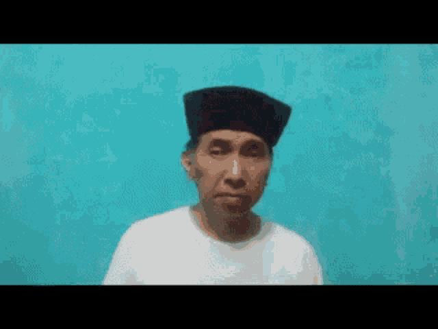 a man wearing a white shirt and a black hat is making a funny face .