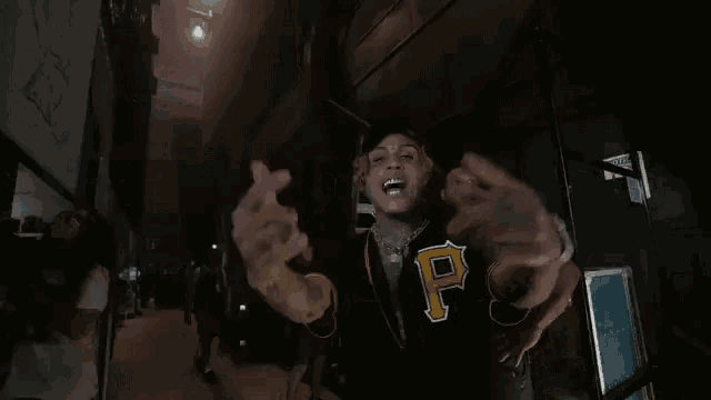 a man in a black and yellow jersey with the letter p on it is making a thumbs up sign .