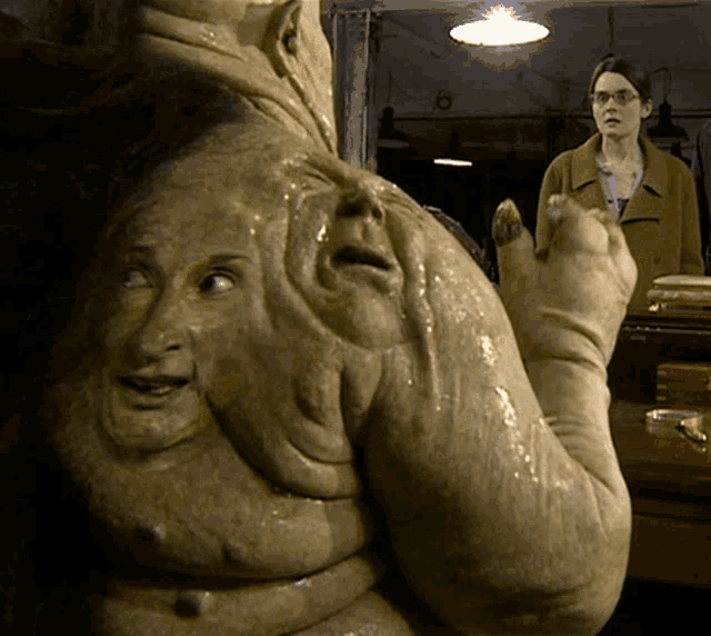 a woman in glasses stands in front of a statue of a person