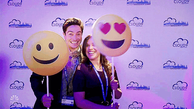 a man and a woman holding smiley faces in front of a wall that says cloud9