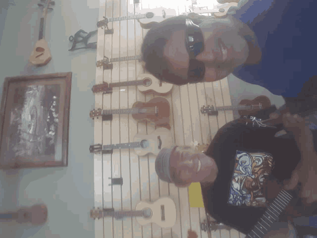 two men standing in front of a wall of guitars