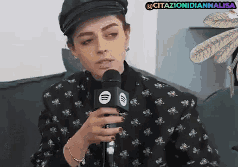 a woman wearing a black hat is holding a microphone in front of her face ..
