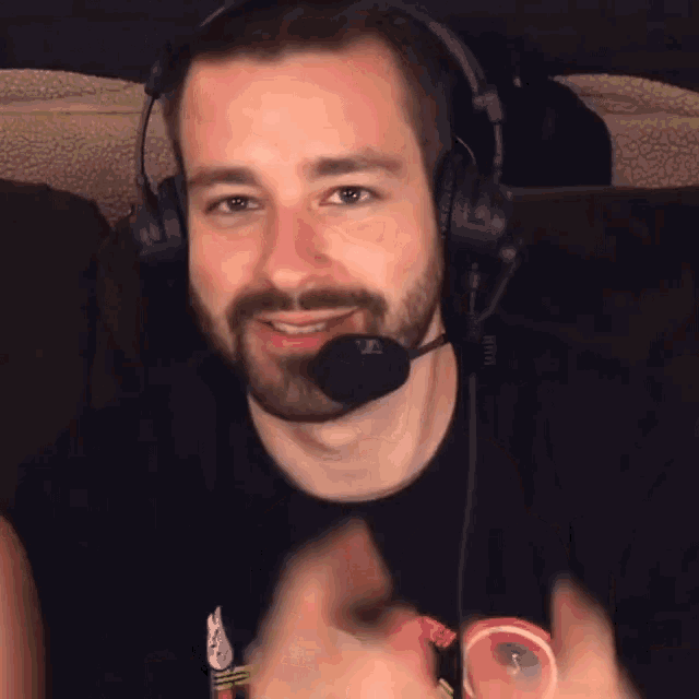 a man with a beard wearing headphones and a microphone giving a thumbs up