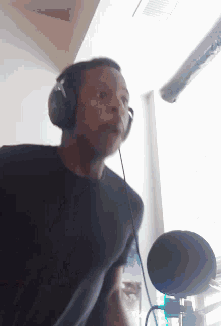 a man wearing headphones is dancing in front of a microphone