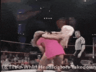 a woman in a pink dress is being lifted by a man in a wrestling ring .