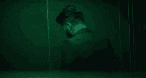 a close up of a man 's face in a dark room with a green light shining on it .