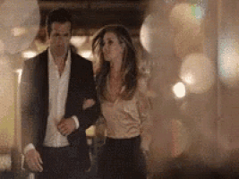 a man in a suit is walking with a woman in a satin shirt .