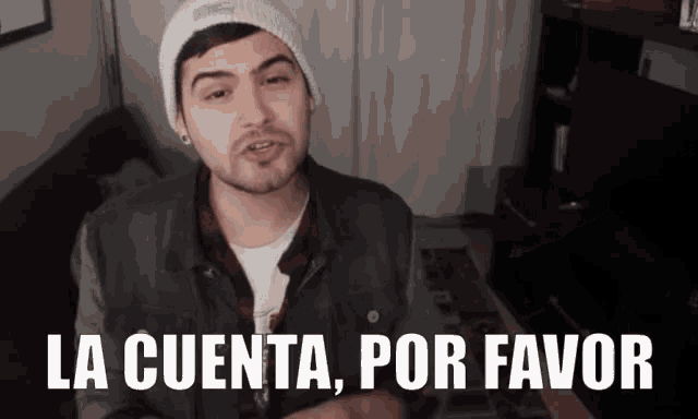 a man wearing a beanie and a denim jacket says la cuenta por favor