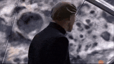 a man in a suit and hat is looking at a painting of the moon .