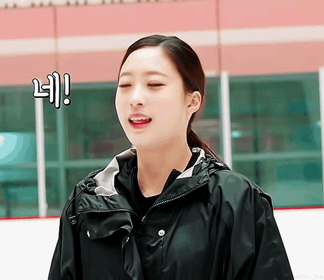 a woman in a black jacket stands on an ice rink