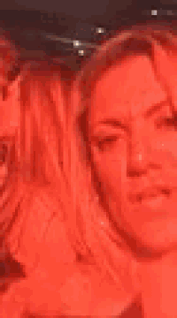 a woman is taking a selfie with a man behind her while a man kisses her on the cheek .