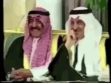 two men in traditional clothing are sitting next to each other on a couch and smiling .