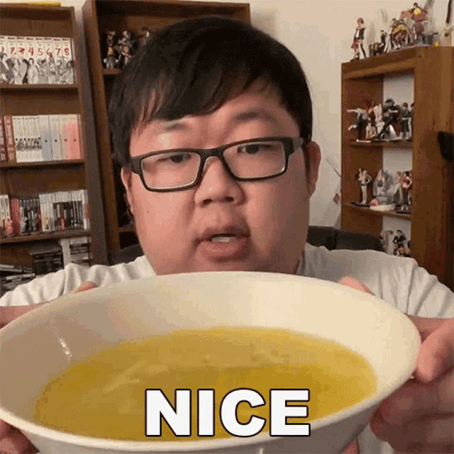 a man wearing glasses is holding a bowl of soup with the word nice written on it