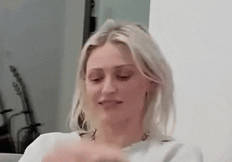 a woman is sitting on a couch with her eyes closed and making a funny face .