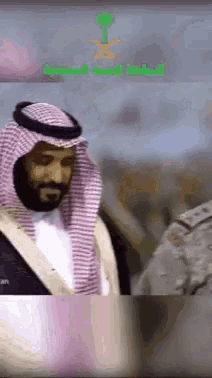 a man in a saudi arabian costume is standing in front of a crowd of people .