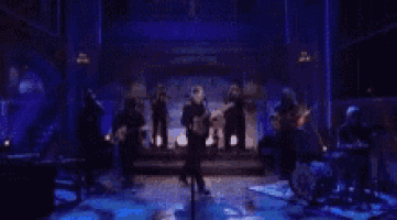 a group of people are standing on a stage in a dark room .