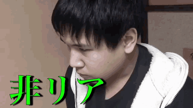 a man in a black shirt and a white hoodie is looking at the camera with chinese writing behind him