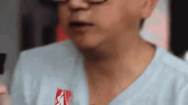 a man wearing glasses is eating a snack from a can .