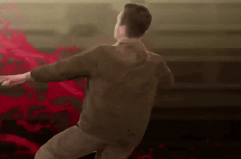 a man in a brown shirt is dancing in front of a red background .
