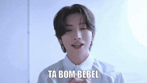 a young man wearing a white shirt is making a funny face and saying ta bom bebel .