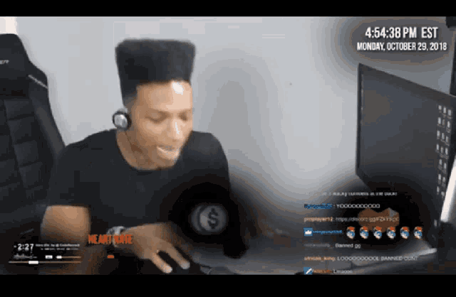 a man wearing headphones sits in front of a computer screen that says monday october 29 at 4:54:38 pm est