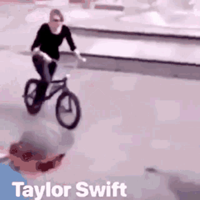 a woman is riding a bike on a sidewalk with taylor swift written on the bottom .