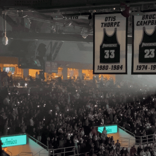 a crowd of people watching a basketball game with banners hanging from the ceiling that say providence