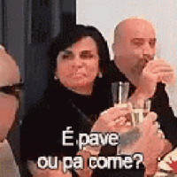 a group of people are sitting at a table drinking wine and toasting .