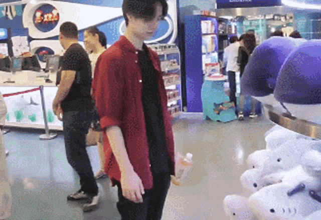 a man in a red shirt stands in front of a display of stuffed sharks