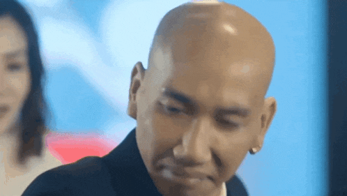 a bald man in a suit and tie is making a funny face .