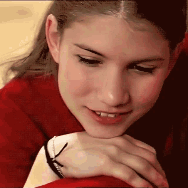 a close up of a girl 's face with a red sweater on