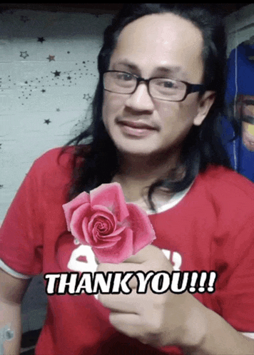 a man in a red shirt holds a pink rose and says " thank you "