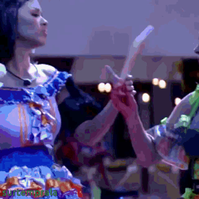 a woman in a blue dress is holding a stick in front of a sign that says surtemporala