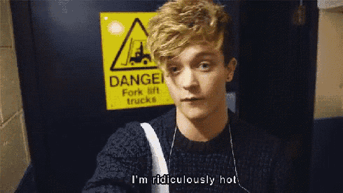 a young man is standing in front of a danger fork lift trucks sign