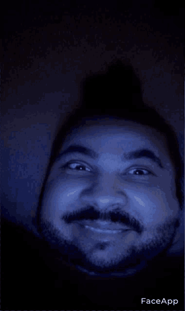 a man with a beard and mustache is smiling in the dark with faceapp written on the bottom