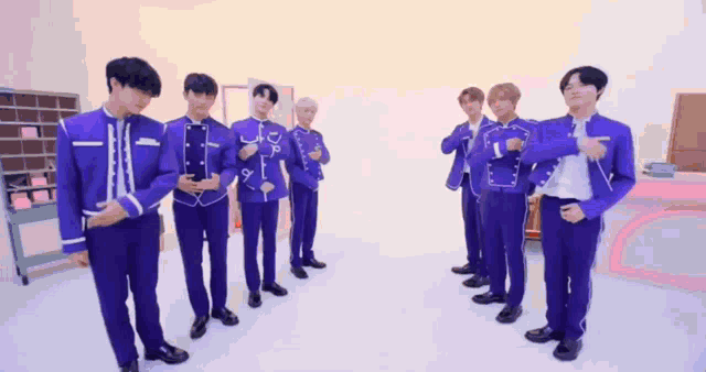 a group of young men in purple suits are standing in a row .