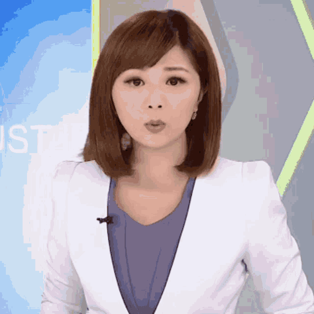 a woman wearing a white jacket and a blue shirt stands in front of a sign that says just