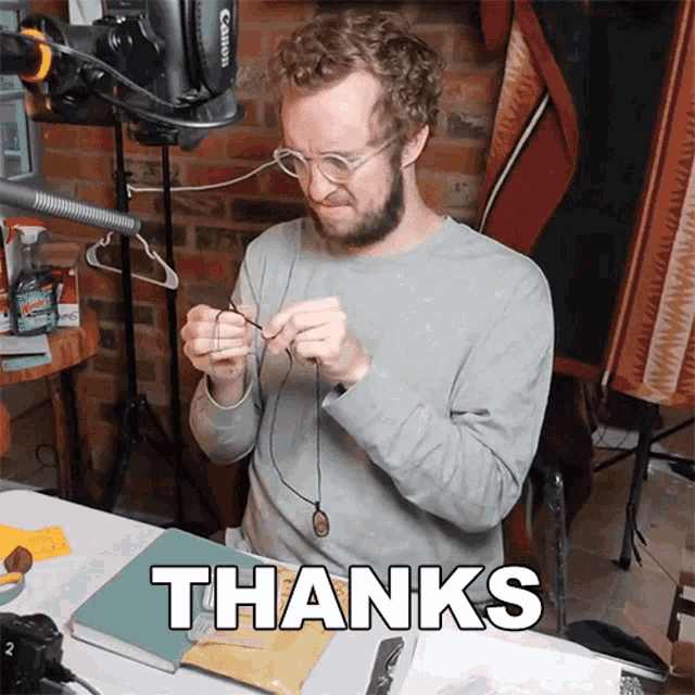 a man sitting at a table with a canon camera in the background says thanks
