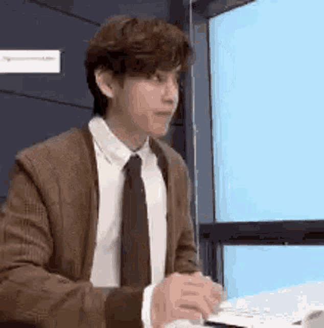 a man in a suit and tie is sitting at a desk in front of a computer .