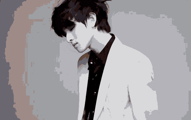 a black and white photo of a man wearing a white jacket and a black shirt .