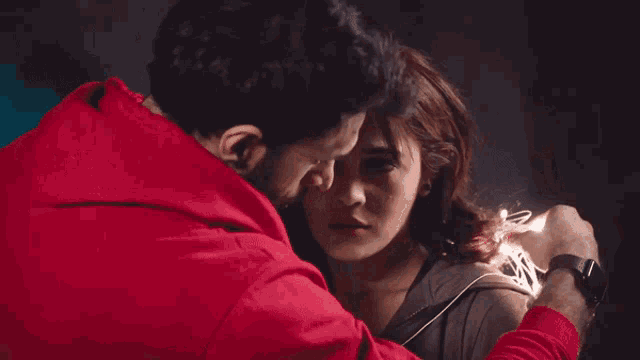 a man and a woman are looking at each other and the man is wearing a red jacket