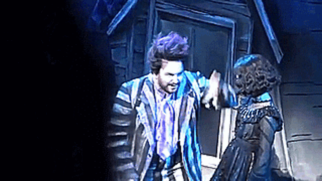 a man and a woman are dancing on a stage in front of a door .
