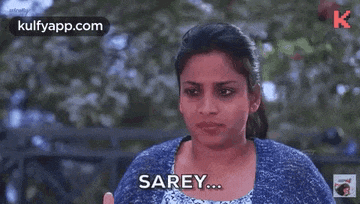 a woman in a blue sweater is making a funny face and saying sarey .