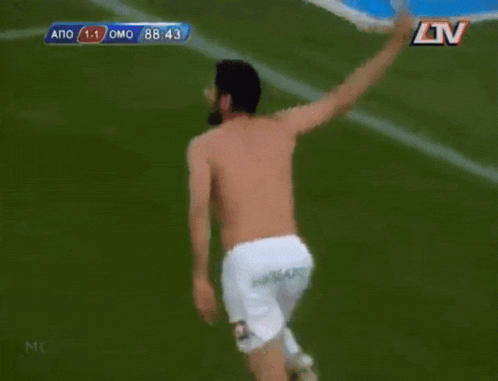 a shirtless soccer player runs on the field with his arm in the air