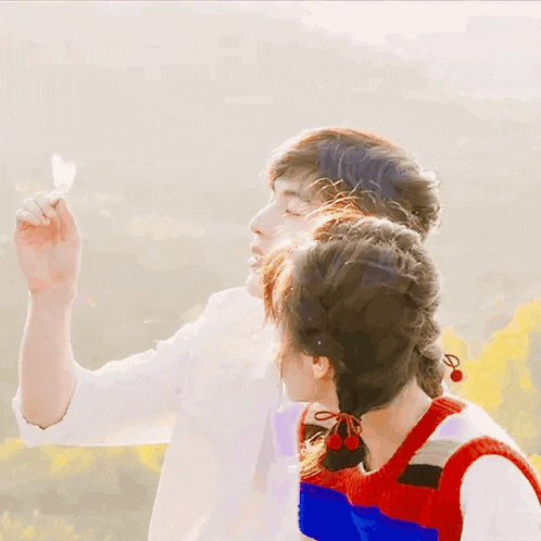 a man and a woman are standing next to each other and the man is holding a flower