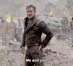 a man in a leather jacket is standing in front of a group of people and talking to them .